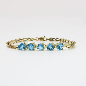 YELLOW GOLD LADY'S BRACELET WITH BLUE HEART CUT STONES.