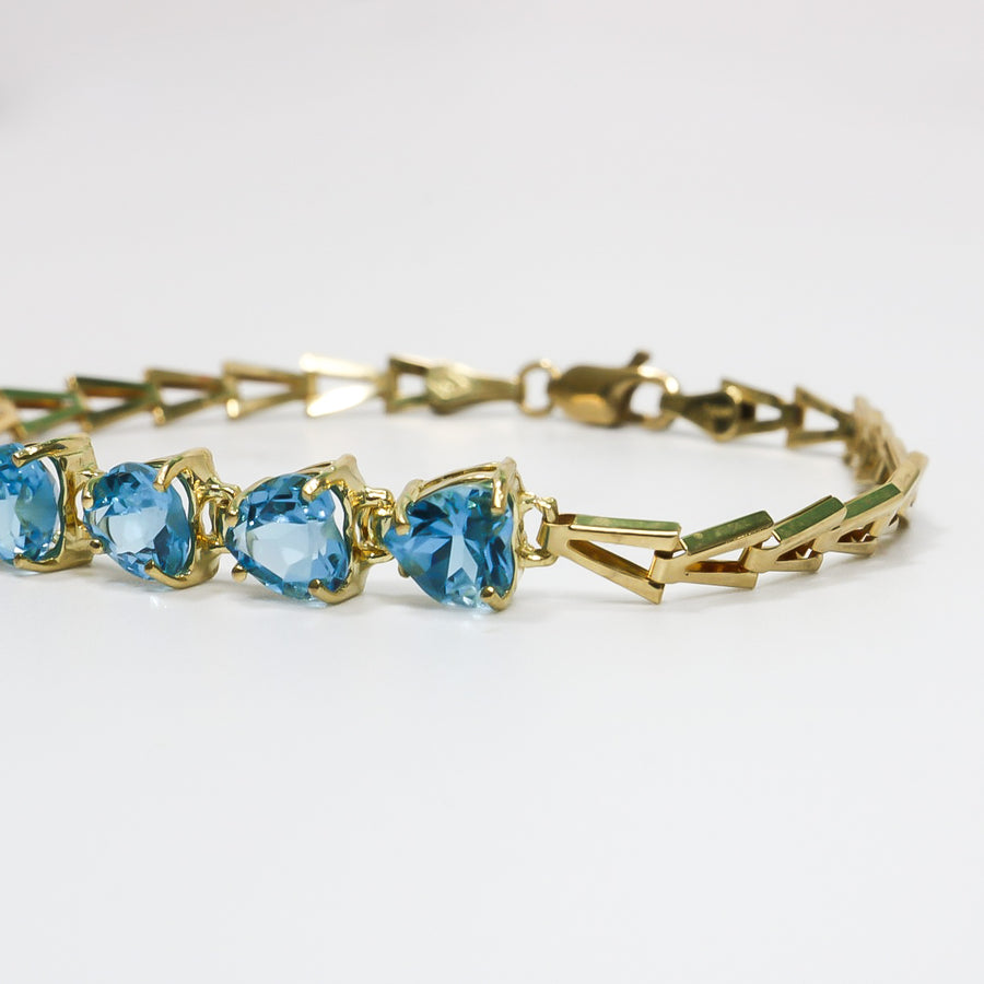 YELLOW GOLD LADY'S BRACELET WITH BLUE HEART CUT STONES.