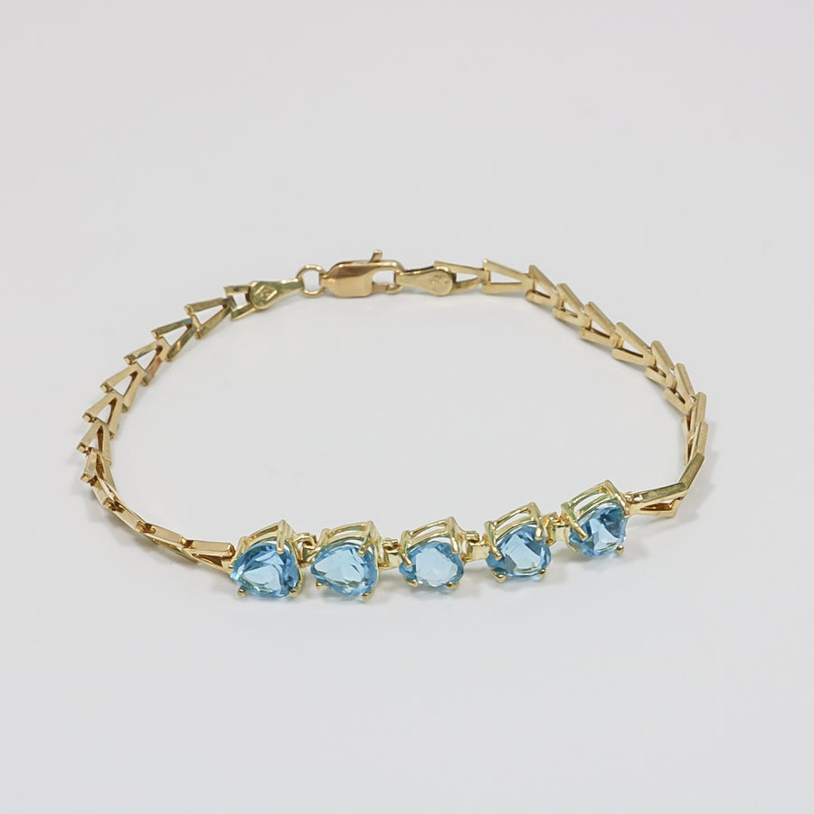 YELLOW GOLD LADY'S BRACELET WITH BLUE HEART CUT STONES.